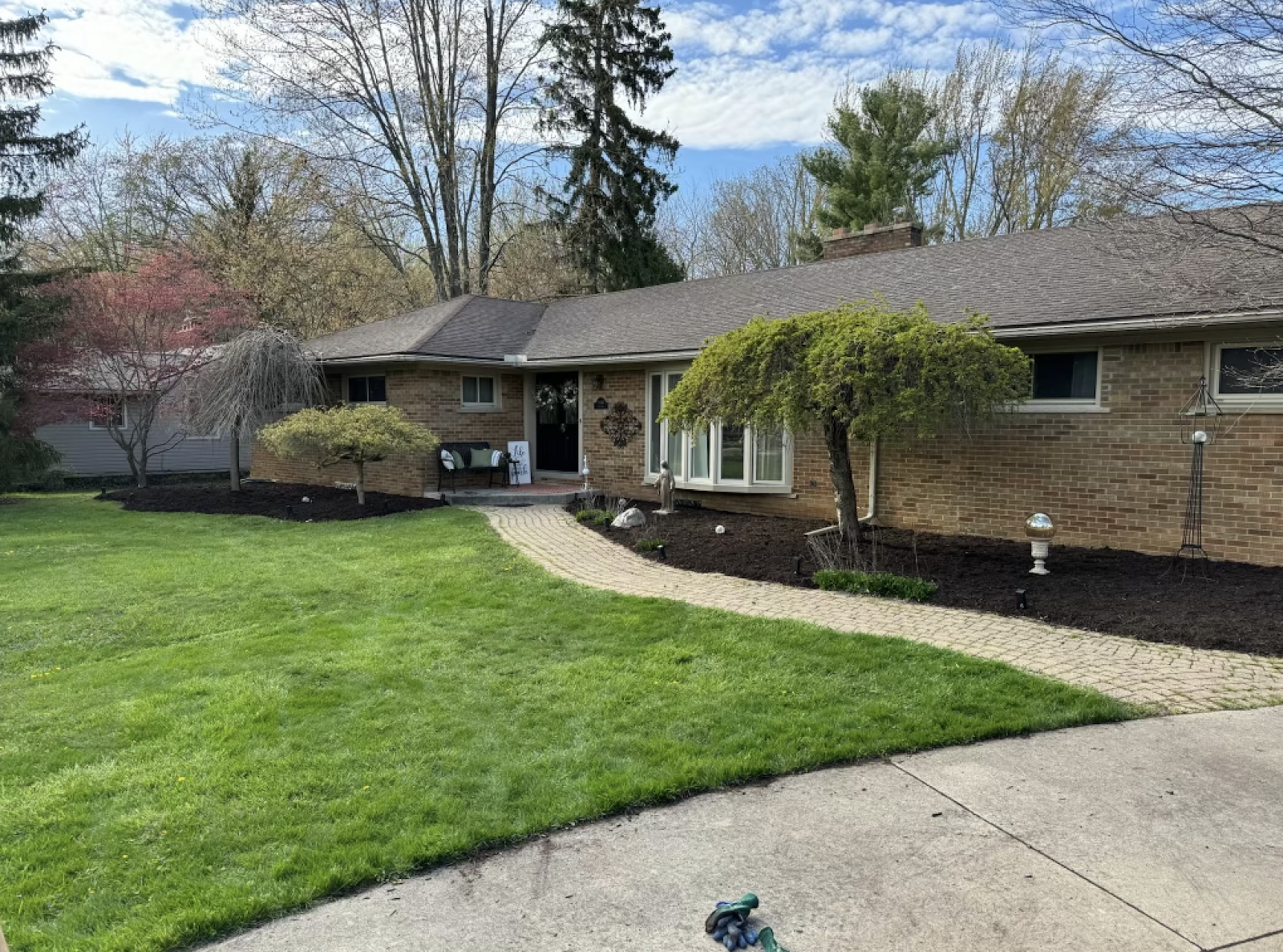 A brick ranch home with manicured front yard, paver walkway, fresh mulch beds, and foundation plantings — full Versa Property Management property care.