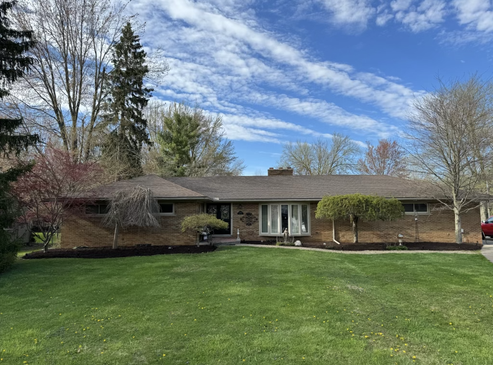 A manicured front yard with mulched bed lining and a clean property entry on a brick ranch in Metro Detroit — Versa Property Management ongoing care.